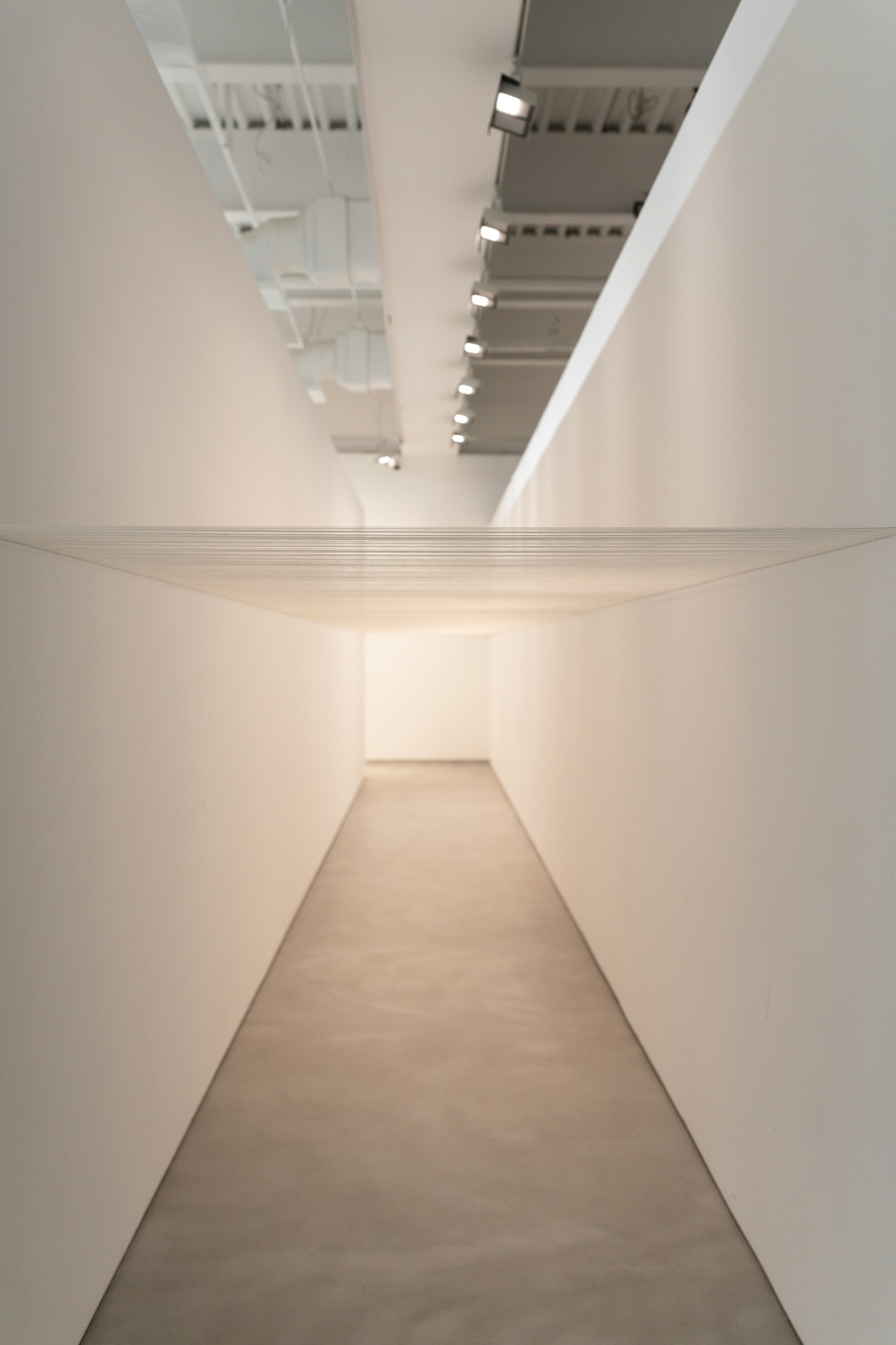 Corridoio interno minimalista, pareti bianche e pavimento luminoso in prospettiva